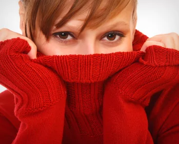 Young woman hiding her mouth behind the neck of her red sweater