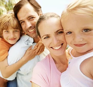 A family with a father, mother, young boy and young girl smiling together